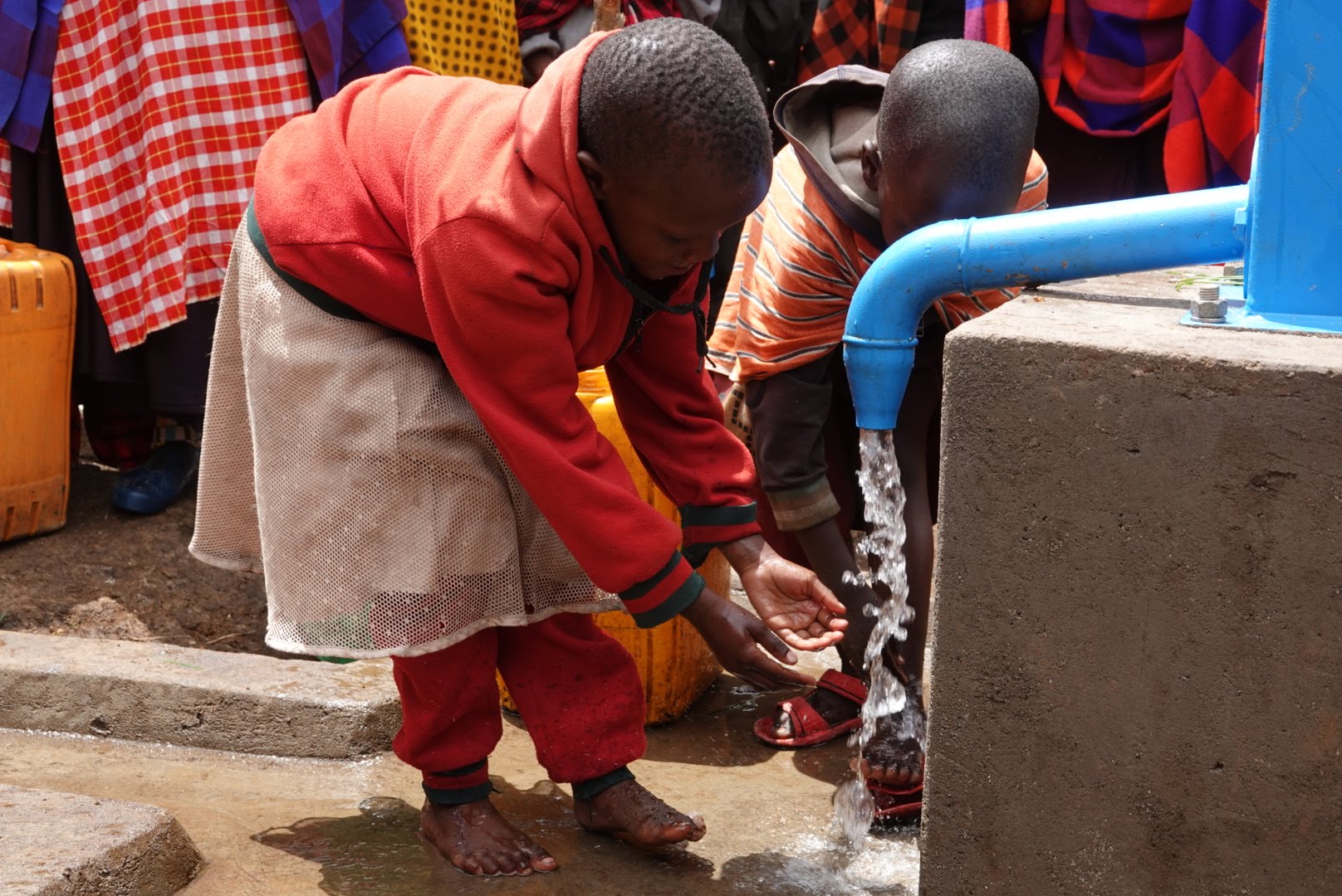 Kindje drinkt water uit een pomp van Naoki Foundation